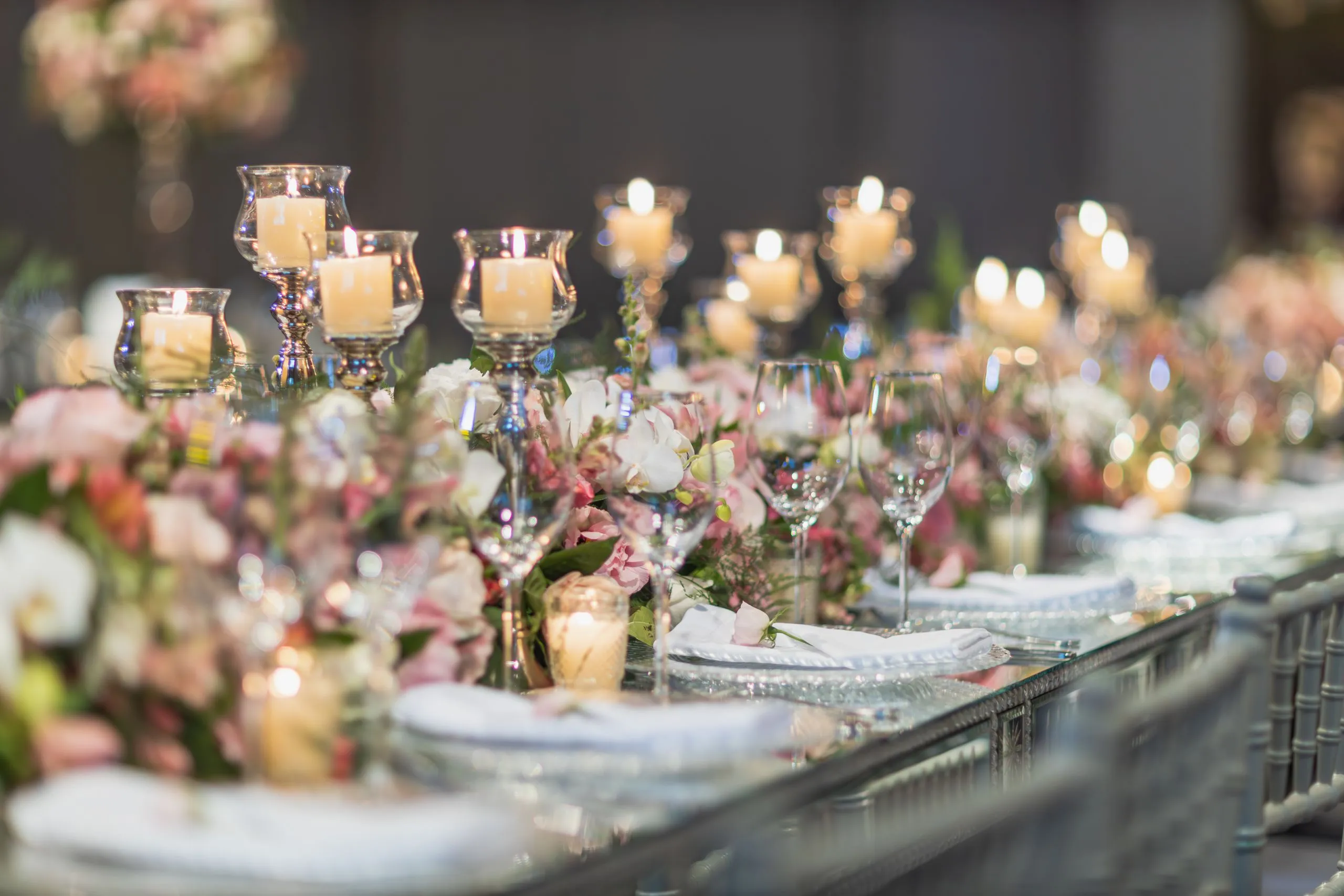 Mesa de boda a la luz de las velas con arreglo floral y copas de cristal